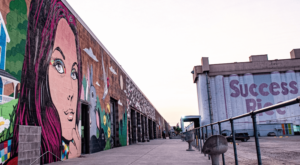 Image of a vibrant and diverse art district in Sawyer Heights First Ward Art District in Houston, Texas. The street is lined with colorful murals, sculptures, and other works of art.